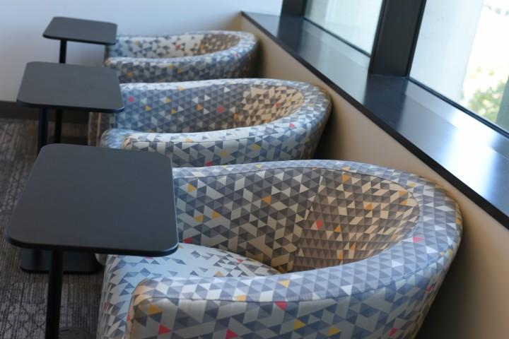 Row of upholstered chairs with small tables.